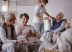 A caregiver checking in with a group of elders in a lounge