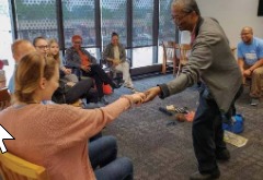 Two people greeting each other warmly in a support group setting
